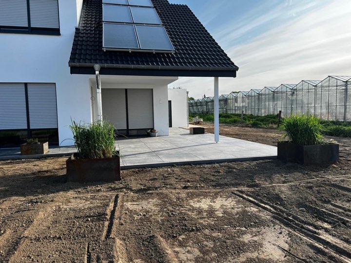 Fertige Feinsteinzeug-Terrasse unter überdachtem Vorbau an einem Neubau bei Herford
